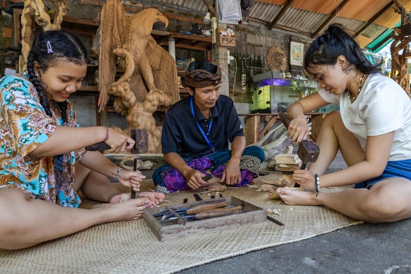 Three people engaged in woodworking, surrounded by tools and wooden sculptures. 1