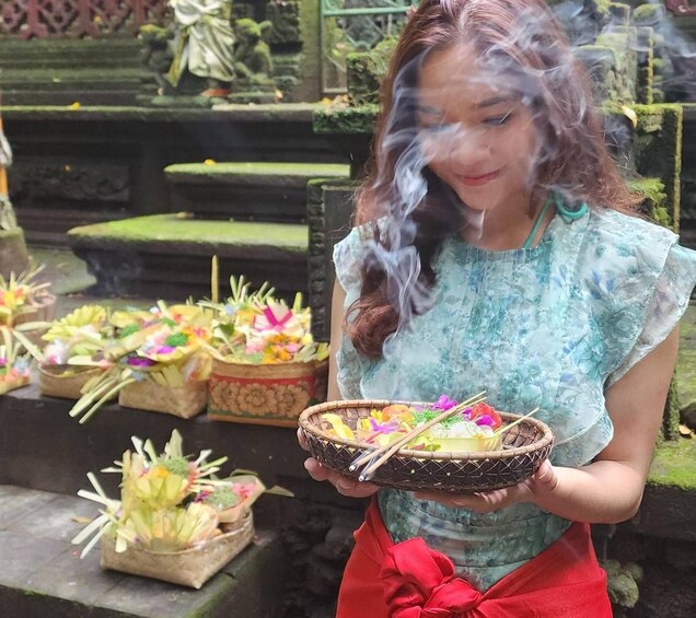 A person holding a ceremonial bowl with offerings, surrounded by similar bowls with flowers and leaves. 3