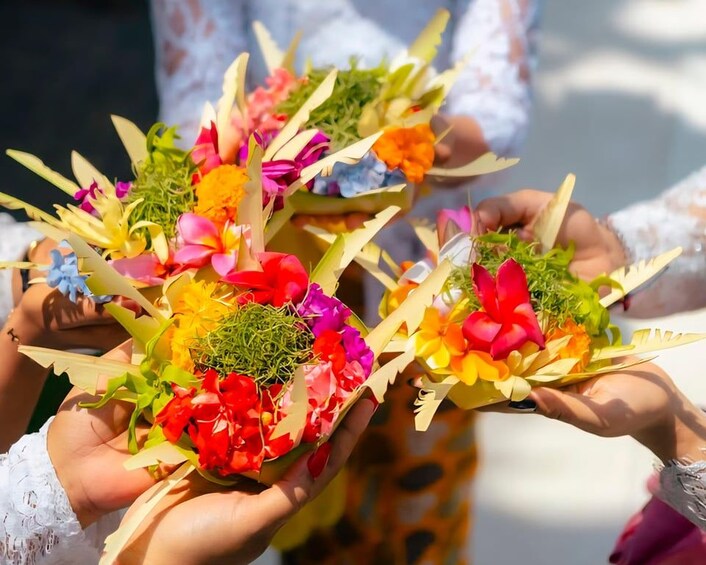 Two hands holding colorful paper flowers with a green center. 4