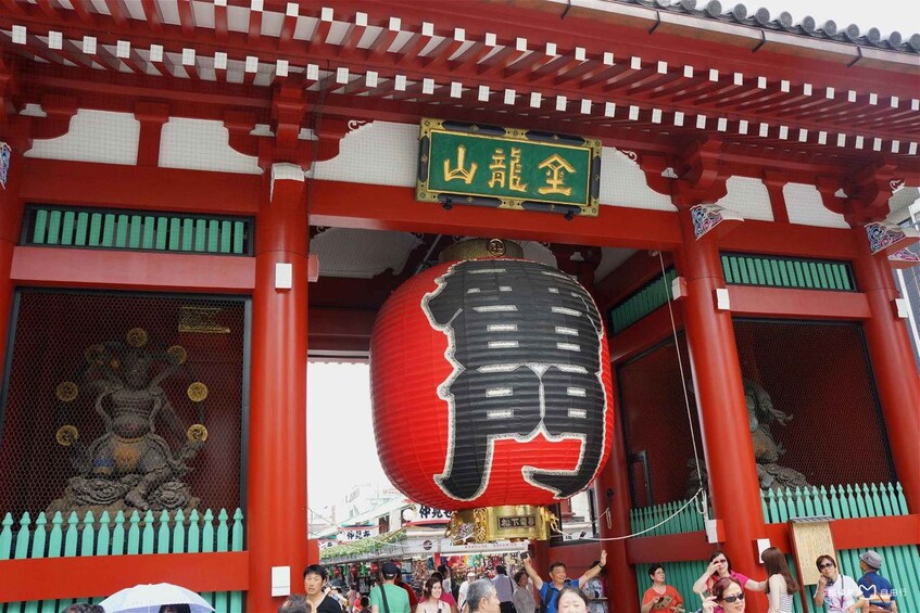 A traditional Japanese gate with a red lantern and a statue of a deity. 5