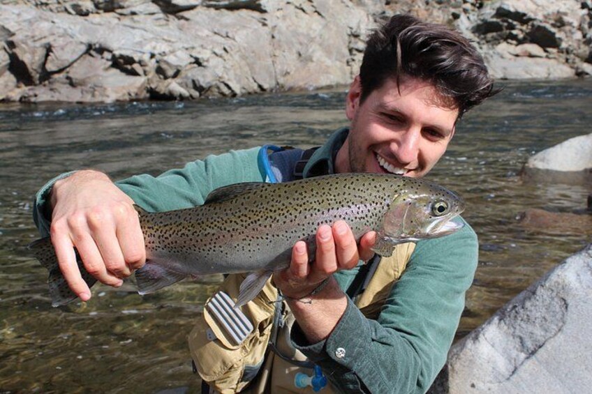 A person holding a fish in a river. 1