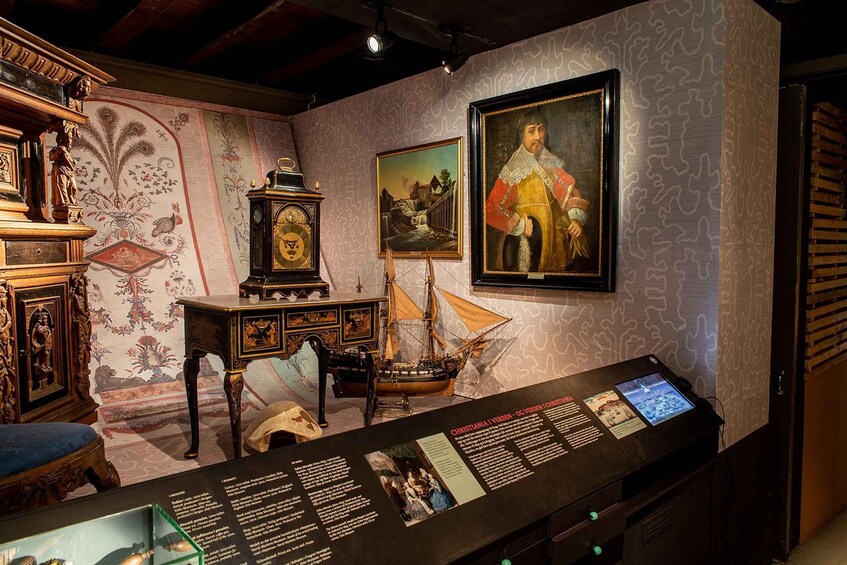 An antique room with a display case, a painting, a ship model, and a clock. 3