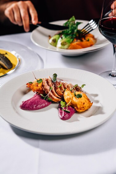 A plate of food with a fork and a glass of red wine. 4