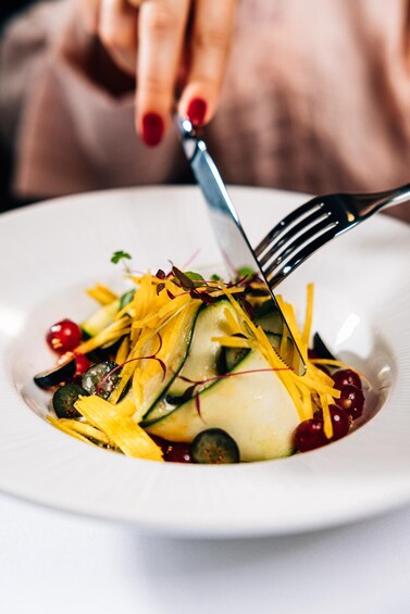 A close-up of a dish with sliced vegetables and garnishes on a white plate. 2