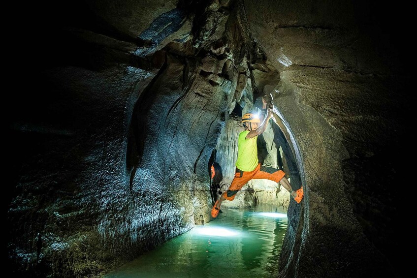 A person rappelling down a rocky cave wall. 2