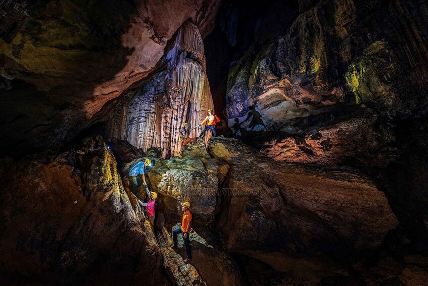 People exploring a cave with stalactites and stalagmites. 1