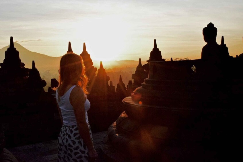 A person standing in front of temple structures with a mountain in the background. 3