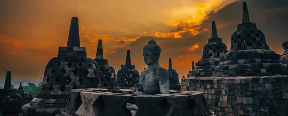 Ancient stone structures with a Buddha statue in the foreground. 1
