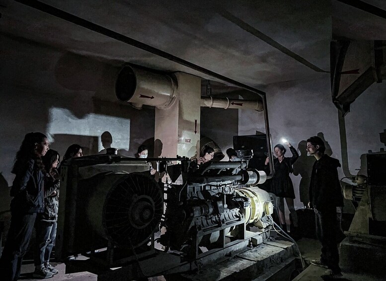 A group of people inspecting a large, industrial machine in a dimly lit room. 2