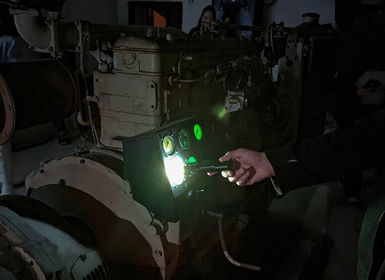 A person holding a device with illuminated gauges and a green light. 1