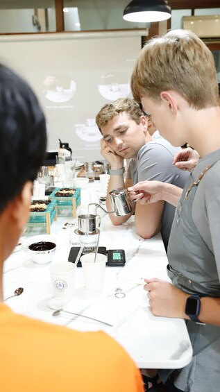 A group of people at a coffee tasting event, with coffee cups and tasting samples on the table. 5