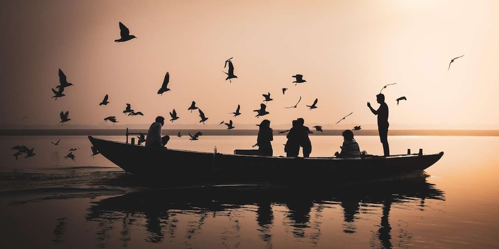 A boat with people on a calm body of water during sunset. 1