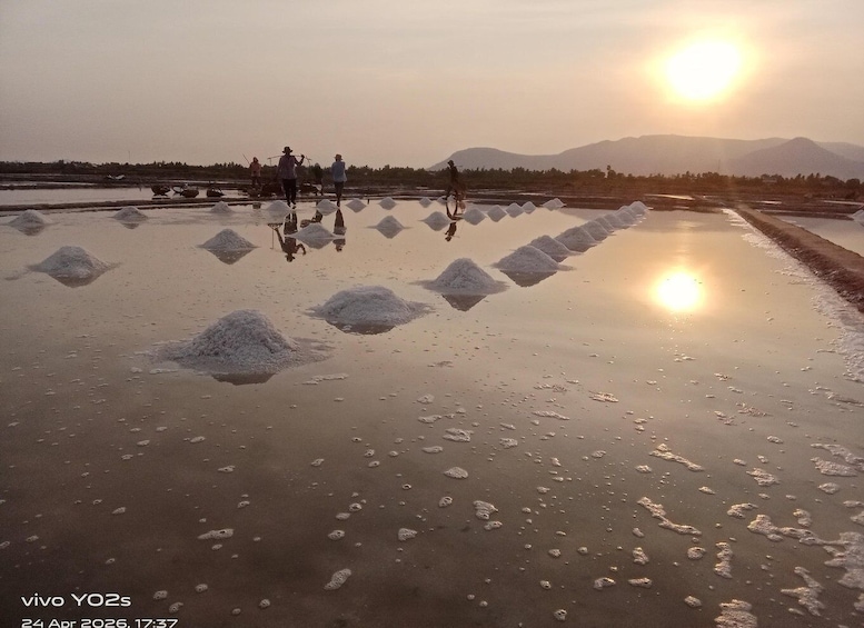 A salt flat with large salt piles and people walking around. 3