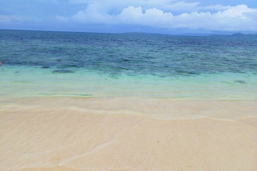 A beach with clear turquoise water and a sandy shore. 2
