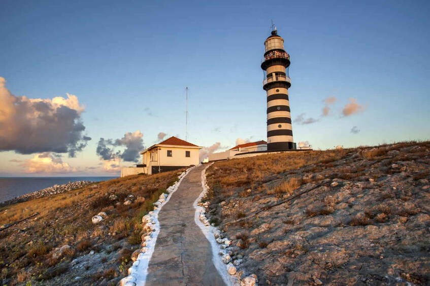 A lighthouse on a hill with a path leading to a building. 3
