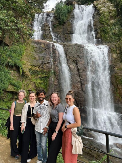 A group of people standing in front of a waterfall. 2