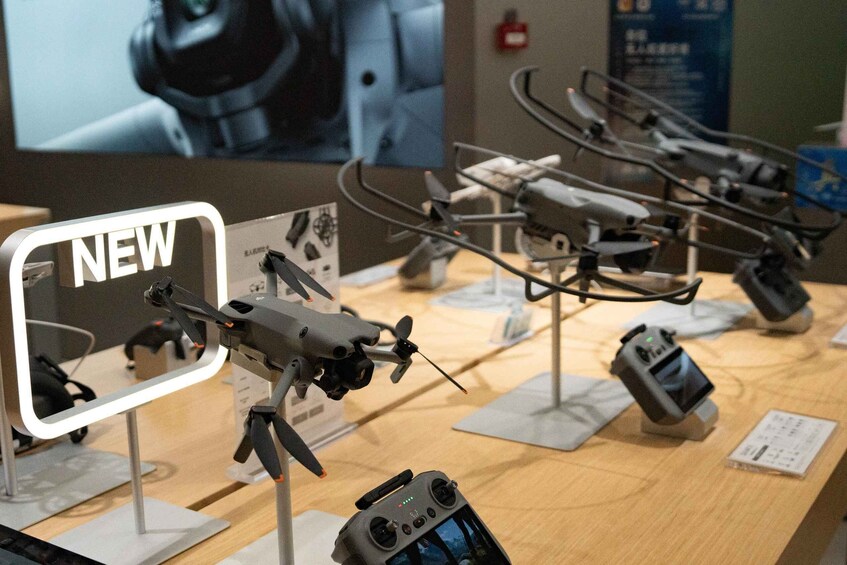 A display of drones with a 'NEW' sign, a camera, and a charging station. 2