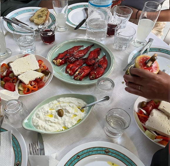 A table with plates of food, including red peppers, olives, and a bowl of yogurt with olive oil. 3