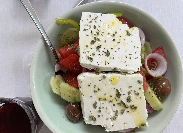 A bowl of Greek salad with feta cheese, olives, tomatoes, and cucumbers. 2