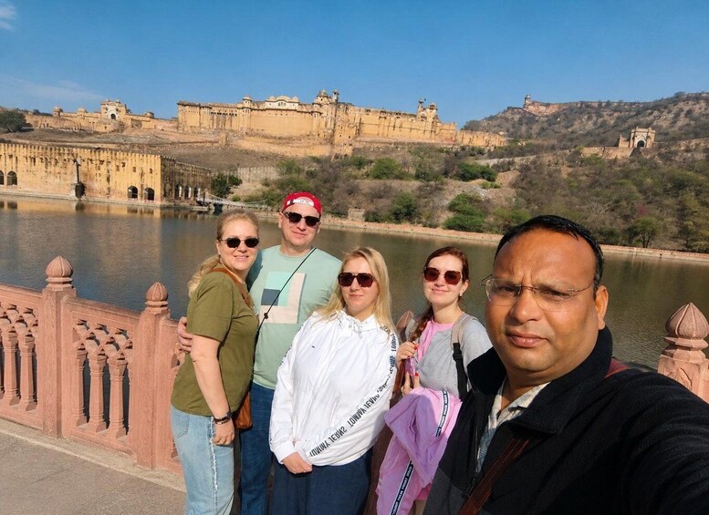 A group of people taking a selfie in front of a historic fort with a river in the background. 1