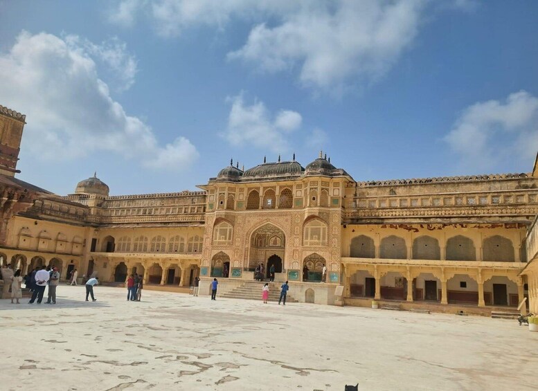 A historic building with intricate architecture, a courtyard, and people walking around. 3