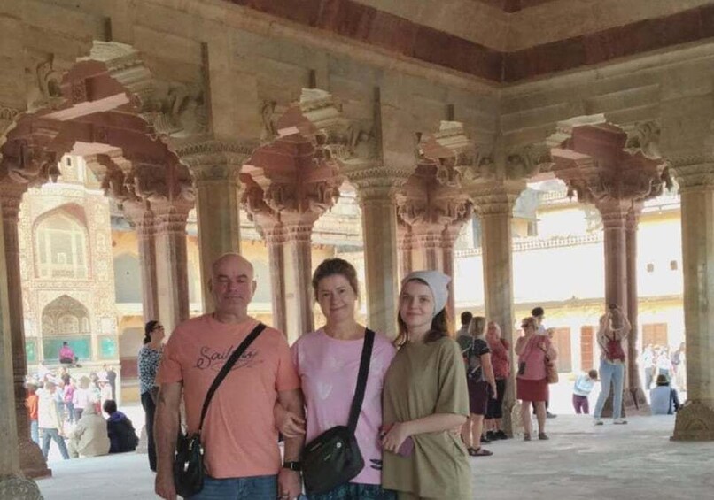 A group of people standing under a large, ornate archway with intricate carvings. 5