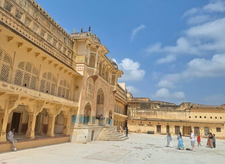 A historic building with intricate architecture, a courtyard, and people walking around. 2