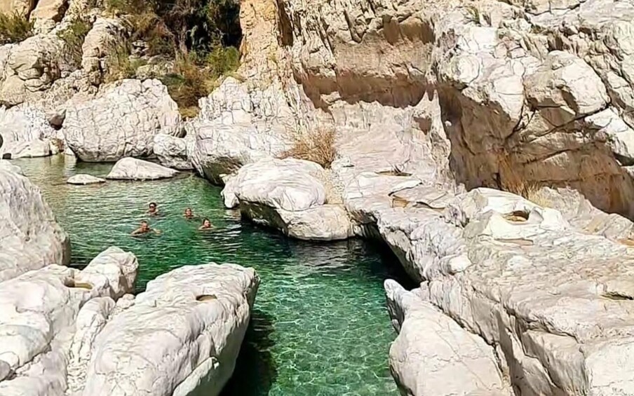 A clear, rocky riverbed with people swimming. 4