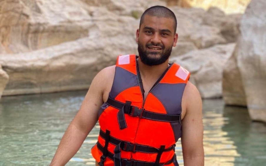 A person wearing a life jacket near a rocky water body. 5
