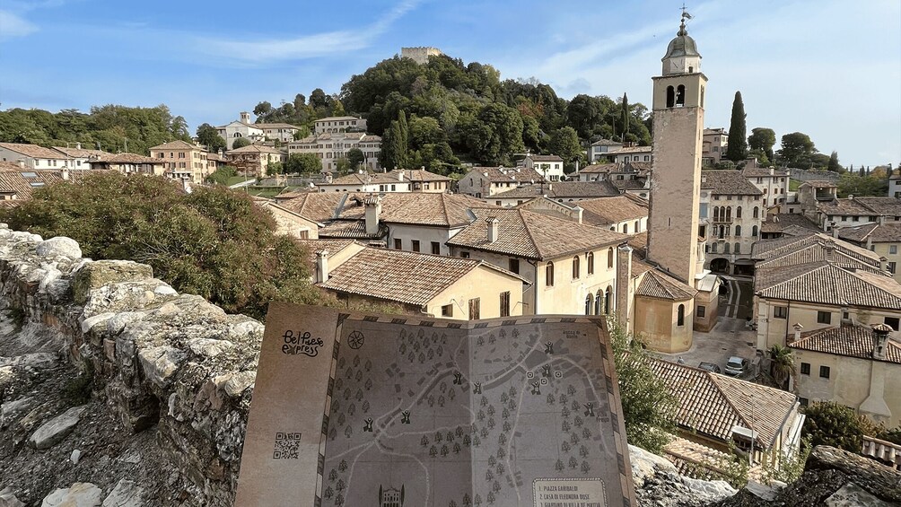 A historic town with a prominent tower, terracotta-roofed buildings, and a castle on a hill. 3