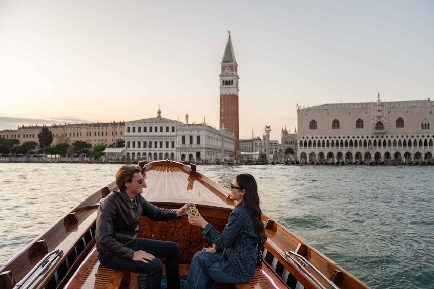A boat with two people, a historic building, and a tower in the background. 1
