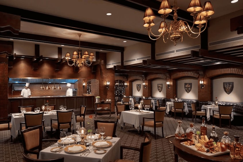 A restaurant interior with multiple dining tables, chairs, and a chef at the counter. 4