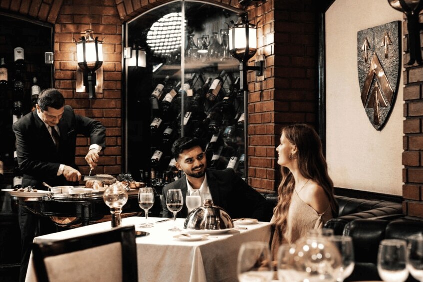 A restaurant interior with brick walls, hanging wine bottles, and a shield-shaped wall decoration. 2