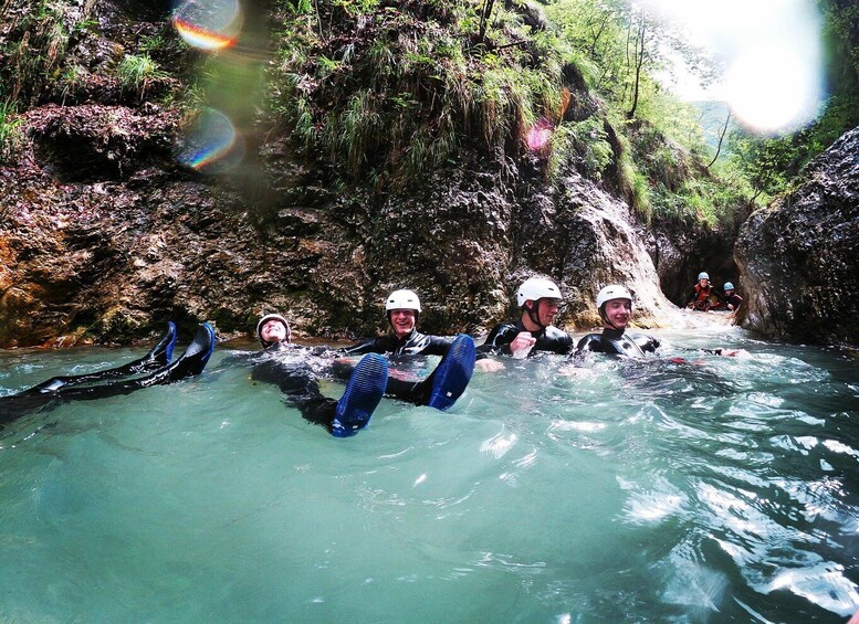 People in water with kayaks, surrounded by rocky cliffs and greenery. 2