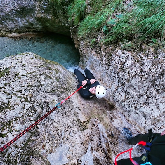 A person rappelling down a rocky cliff with a rope. 1