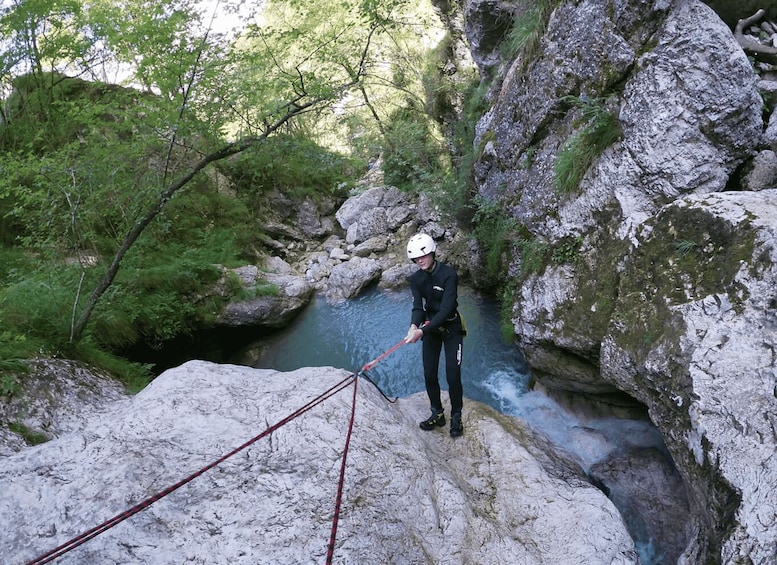 A person rappelling down a rocky cliff into a river. 3