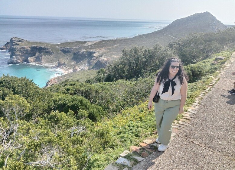 A person walking on a coastal path with a view of the ocean and a mountain in the background. 2