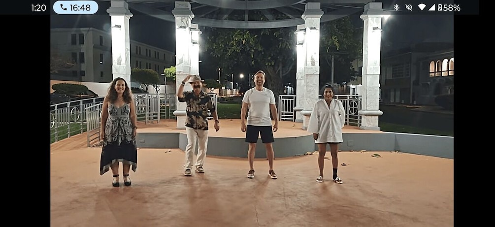 A group of people standing in a circular plaza with columns and a fountain in the background. 1