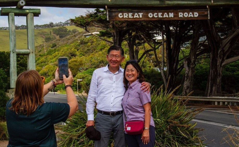 Three people posing in front of a sign that reads "Great Ocean Road". 3