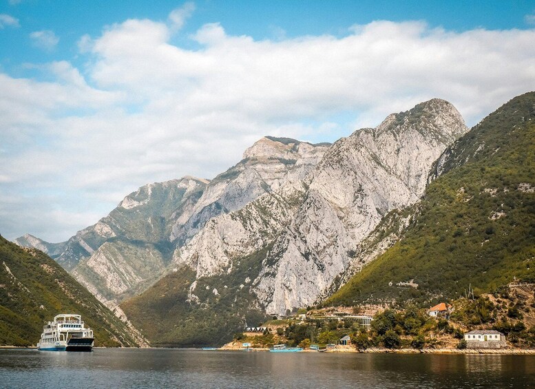 A boat on a lake with mountains in the background and a small settlement on the shore. 2