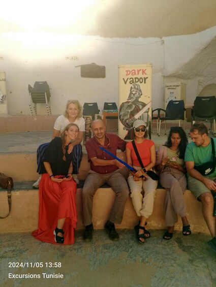 A group of people sitting on steps in a covered area with a banner reading "Park vapor" in the background. 5