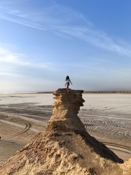 A person standing on a rock formation in a desert landscape. 4