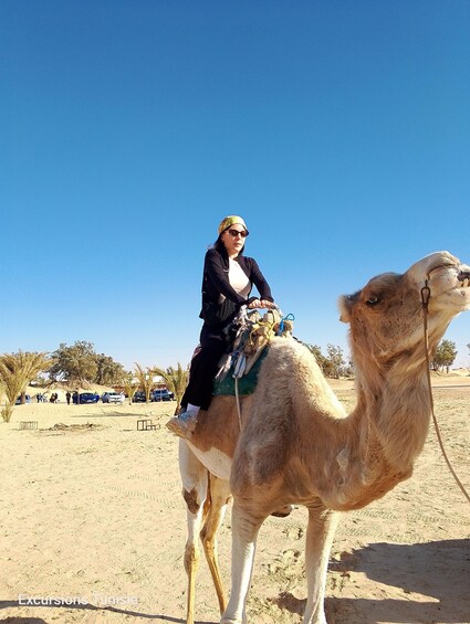 A person riding a camel in a desert setting. 2