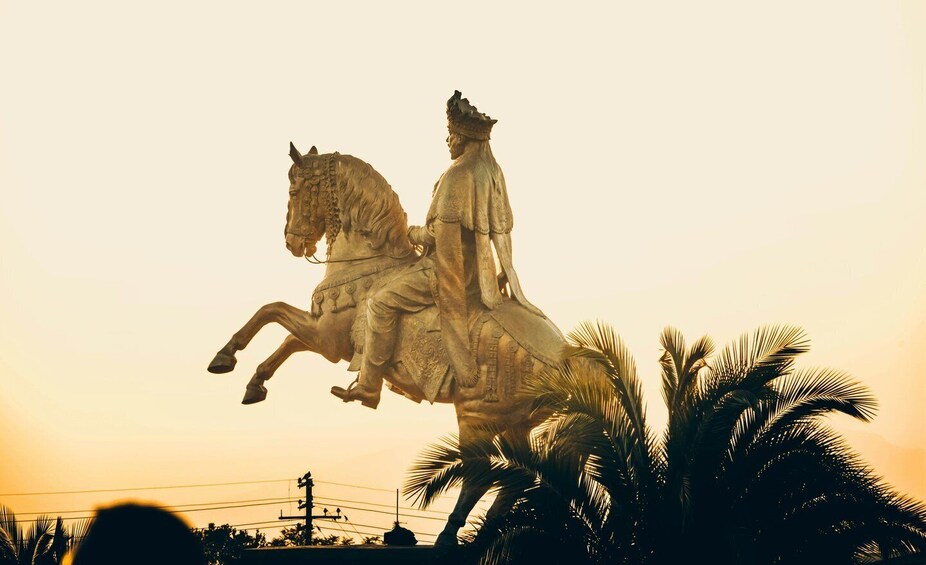 A statue of a man on a horse, set against a sunset sky. 3