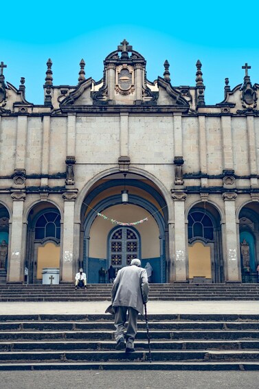 A grand building with a large arched entrance and a clock tower. 1
