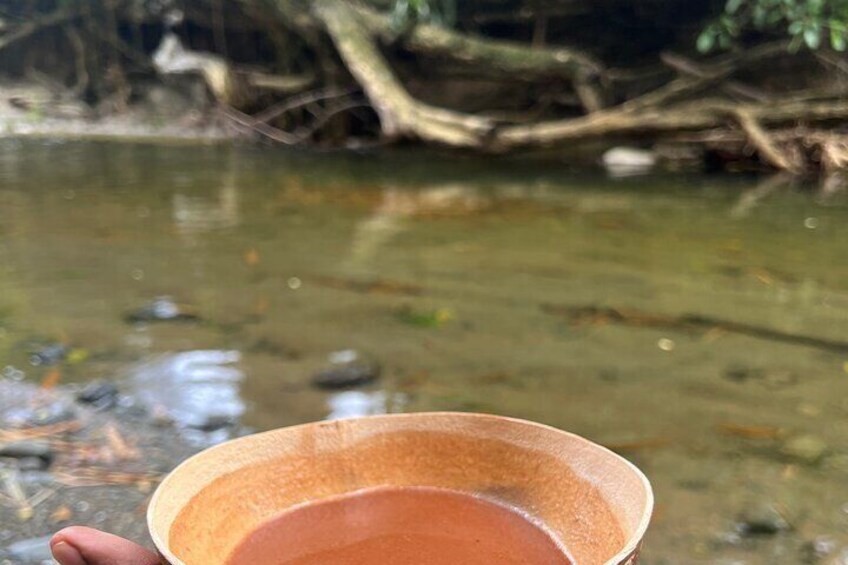 A hand holding a bowl over a stream. 3