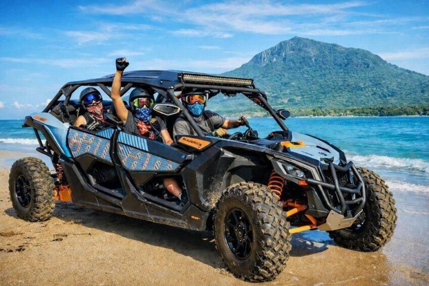 Un véhicule tout-terrain à quatre places sur une plage, avec une chaîne de montagnes en arrière-plan. 1