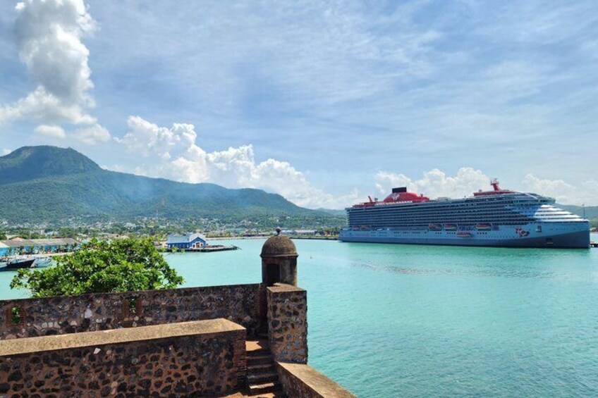 Un grand navire de croisière était amarré dans un port aux eaux turquoise, avec un mur de pierres et une montagne en arrière-plan. 5