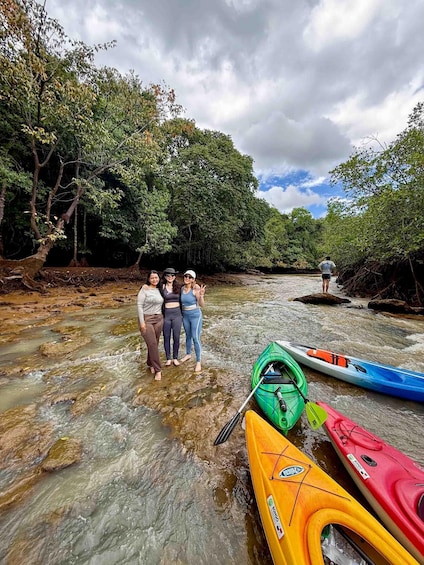 Three people standing by a river with kayaks. 1