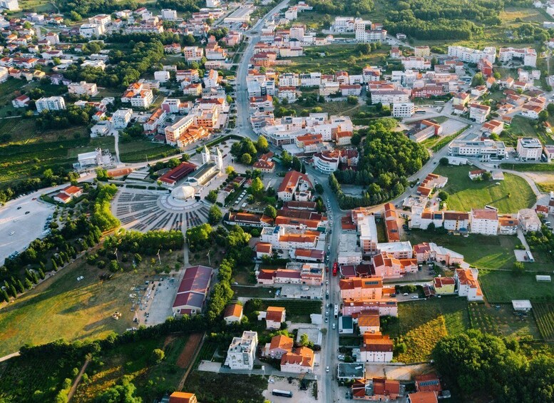 An aerial view of a town with a central roundabout, surrounded by residential buildings and green spaces. 3
